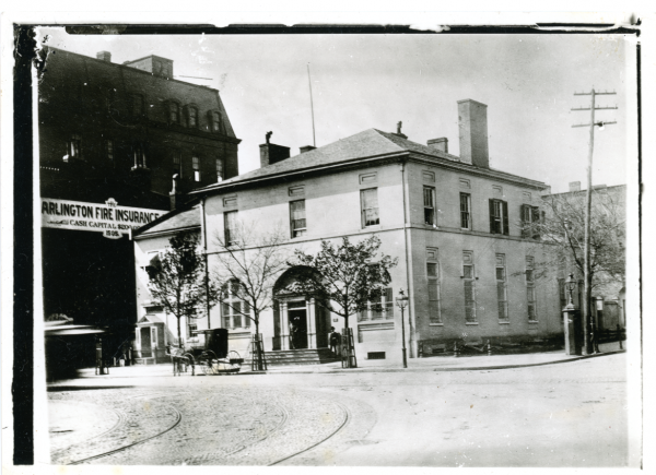 black and white photo of a side view of two story building with carriage out