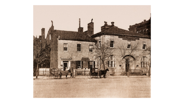 black and white photo of two story building with carriages out front