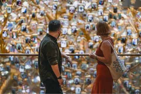 Two people at balcony railing looking at interior of hall